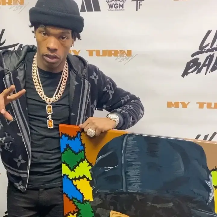 Lil Baby holding the commissioned canvas at the My Turn press wall